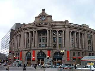 Beige stone building with columns on the façade and a clock at the top