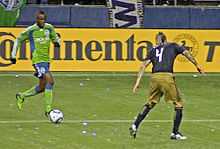 A footballer dribbles towards an opposing player during a match