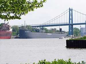 Gray barge sailing under a bridge