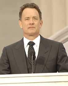 A man wearing a black suit including a white shirt and a tie with polkadots.