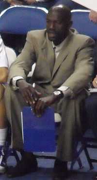 An African-American man sitting and wearing a tan suit