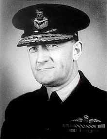 Head-and-shoulders portrait of man in dark uniform with ribbons and pilot's wings on chest, wearing peaked cap