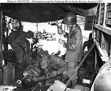 Medics treat a pair of injured men in a tent in the middle of a jungle