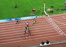 Eight men approach the finishing line of race at a stadium track