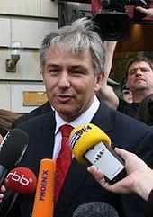 Man outside building, in front of bank of microphones