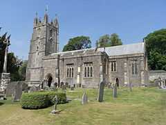 Stone building with square tower. In the foreground are gravestones