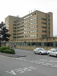 Modern building with 7 floors of windows. In the foreground is a road with cars.