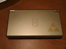 A gray handheld video game device with the Triforce logo in the bottom-right corner, which looks like three triangles touching at their points.