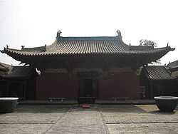 The Wanfo Hall of Zhenguo Temple. The tiled roof is decorated with small, ornate dragons. There is one door opening to a bricked courtyard