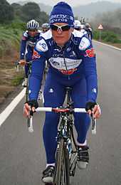 A cyclist wearing a blue and white cycling uniform while riding a bike.