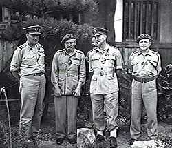 Full-length outdoor portrait of four men in light-coloured military uniforms