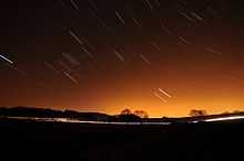 Short streaks of light on a dark sky, showing star trails that were photographed with a long exposure.