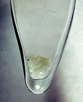 Glass vial of brownish-white snow-like precipitation of plutonium hydroxide