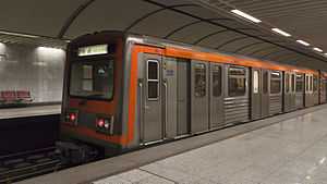 Grey subway train with orange stripe in a station
