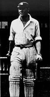 A cricketer leaving the pavilion holding a bat