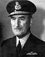 Head-and-shoulders portrait of man in dark  uniform with peaked cap and pilot's wings on left-breast pocket