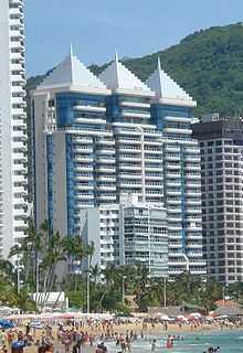 Three 21-story blue-and-white-clad triplet condominiums loom over a white 9-story, next to an older brown-tone 20-story