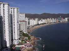 High view of the beachfront condos and hotels on the left, the long curved beach, Pacific ocean on the right