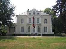 White building with law in front and flagpoles with flags flying