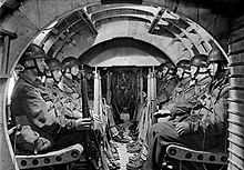 Interior of a glider with men sitting in rows along both sides