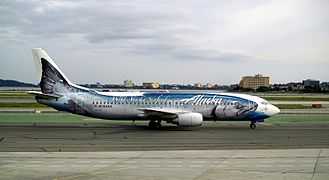 Right side view of an aircraft taxiing on the ground with a giant salmon painted on the fuselage.