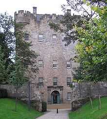 A tall stone building from the 15th century with trees bordering to the sides