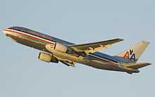 Sideview of 767 on climbout against a pale blue sky. A blue, white and red cheat-line runs the full length of the fuselage, above which says "American". The vertical tail sports two "A"s, between which is a simplified eagle.