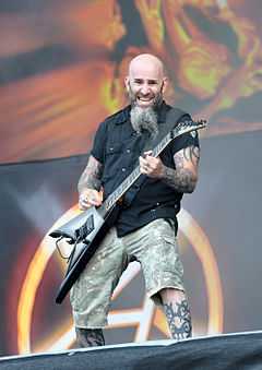 Bald, bearded, tattooed man playing guitar onstage