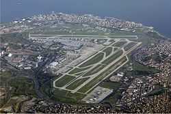 An aerial view of an airport with three runways and several taxiways arranged around a terminal