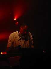 A man with headphones performs at DJ mixing desk.