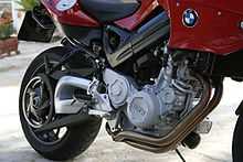 Close up view of engine and rear wheel of a red motorcycle parked concrete