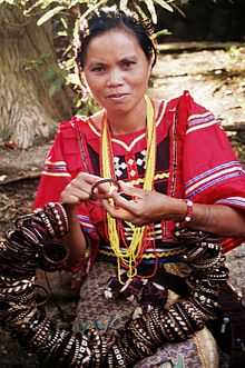 Woman in red decorated blouse making bracelets