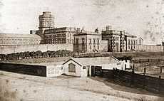 A line drawing of a large Victorian building in the background. In the foreground there is a representation of a small inn called the Bowling Green.