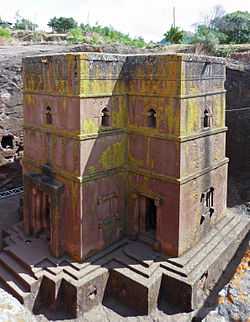 A picture of a pick-coloured building intact inside of a large, square hole.