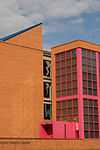 An orange brick building with pink window frames and a blue roof