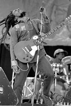 Black and white image of Bob Marley on stage with a guitar