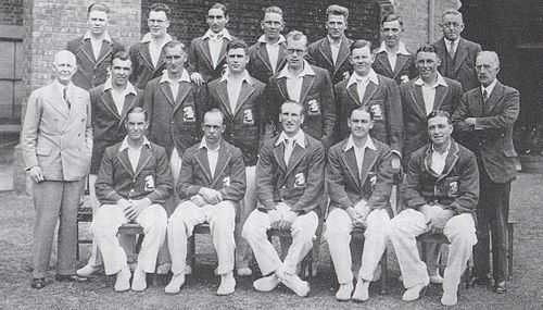 A cricket team arranged in three rows. Seventeen men are dressed as players, the other three men are in suits.