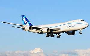 Quarter view of quadjet on approach over clouds.