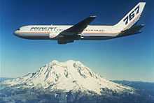 Boeing twin engine jetliner in flight near a snow-capped mountain.