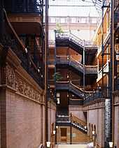 A photograph of a building interior showing stairs climbing up five storeys to the final floor where we can see the glass roof.