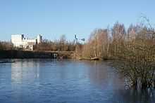  Large pool with scrub on the right and a large white industrial building in the background