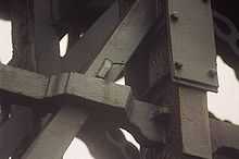 Iron members of the bridge, one showing a visible crack and one repaired by steel sandwich plates bolted around it