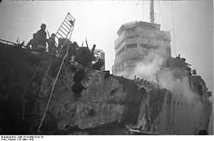 large holes in side of the ship. A ladder leads to the dock. There is also evidence of a fire.