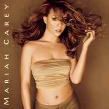 Image shows Carey in a beige sleeveless and mid-baring top, with darker matching pants. Her hair is long and golden-auburn, and is flowing in the air. her left hand is touching the flowing tips of her hair. She has a jeweled belt along her naval, with the words "Mariah Carey" written along the album cover.