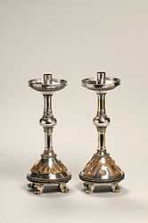 Pair of silver candlesticks, ornately decorated with heart shapes and scroll patterns.