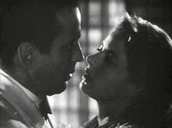A black-and-white screenshot of a man and woman close together appearing ready to kiss.