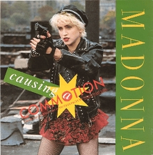 A young woman with short cropped blond hair is pointing towards somebody while holding a gun. She is wearing a red skirt and black jacket and gloves. On her left, the word "Madonna" is written in green and on the center of the image, the word "Causing a Commotion" is written in capitals.