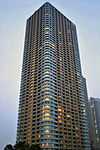 Ground-level view of an orange and white, rectangular, window-dotted high-rise