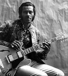 A black-and-white photo of Berry holding a guitar, seated