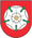 A coat of arms depicting a white flower in the middle that has a yellow stamen and green leaves all on a red background